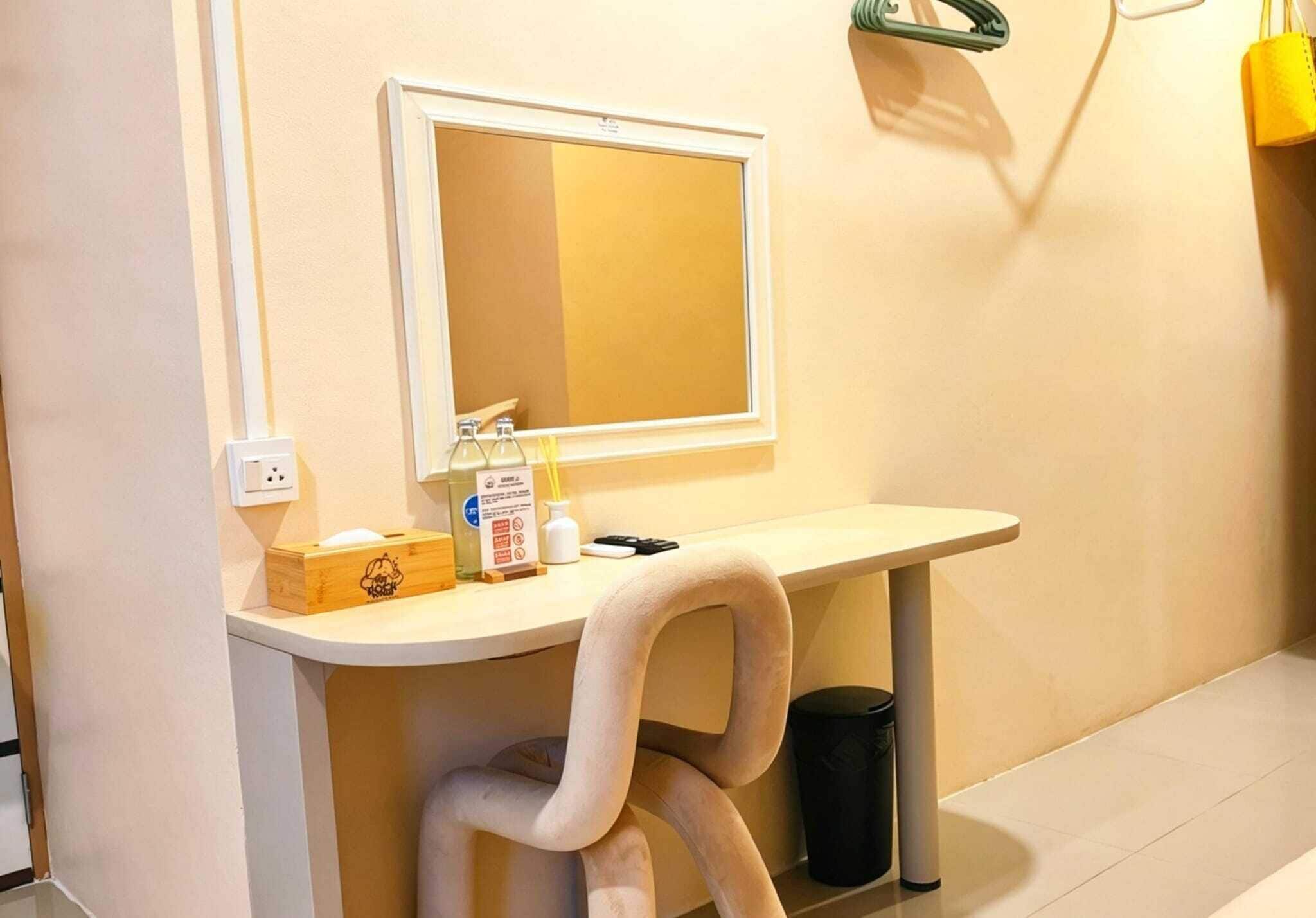 A bathroom with a white sink, a mirror, a trash bin, and a towel rack.