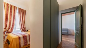 A bedroom with a bed, curtains, and a view of a hallway. - GuestHost - Rione Prati Apartment B (Rome)