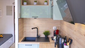 Eine kleine Küche mit integriertem Spülbecken, Holzschränken und einer Arbeitsplatte.