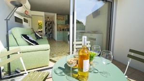Ein Balkon mit Esstisch, einer Couch und einem sichtbaren Küchenbereich hinter den Glastüren.