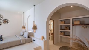 A modern bedroom with a bed, bedside lamps, a built-in shelf, and a small rug. - Villa Calipso (Gili Trawangan)