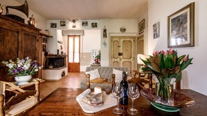Un accogliente soggiorno con camino, arredi in legno e un tavolo da pranzo apparecchiato con bicchieri da vino e un vaso di fiori.
