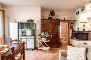 A cozy living room with a wooden table, a green cabinet, and a fireplace.