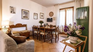 Un soggiorno accogliente con un tavolo da pranzo in legno, un divano e una TV fissata al muro.