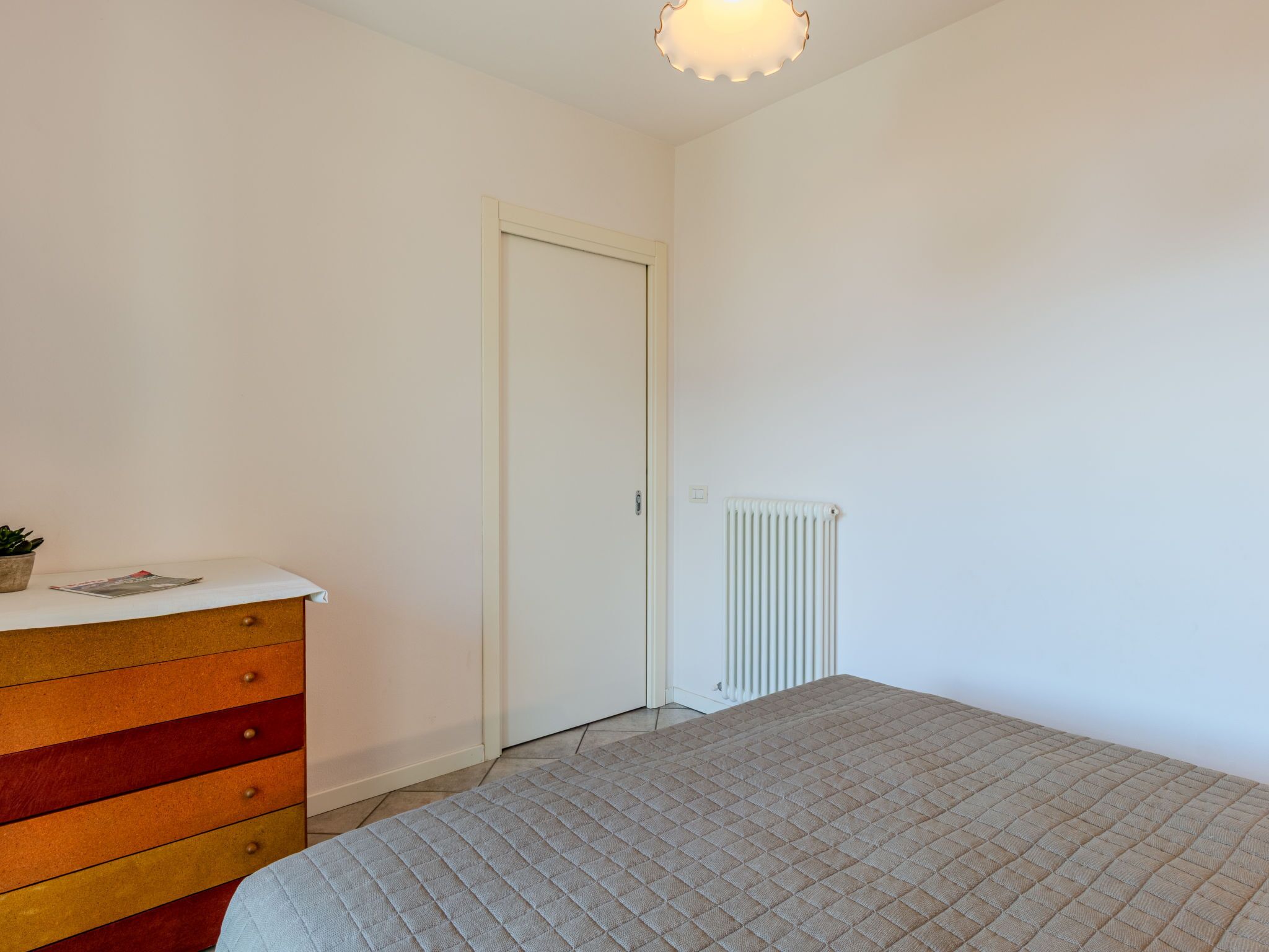 Ein Schlafzimmer mit Bett, Schminktisch, Heizkörper und Tür.