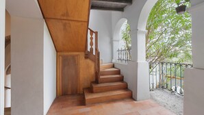 A wooden staircase with a white wall and a metal railing.