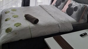 A hotel room with a bed, a small table, and a view of a cityscape through large windows. - RnM Haven in Tsavo Apartments 13kms from JKIA
Walk to Stylish,Clean & Comfy Stay (Nairobi)