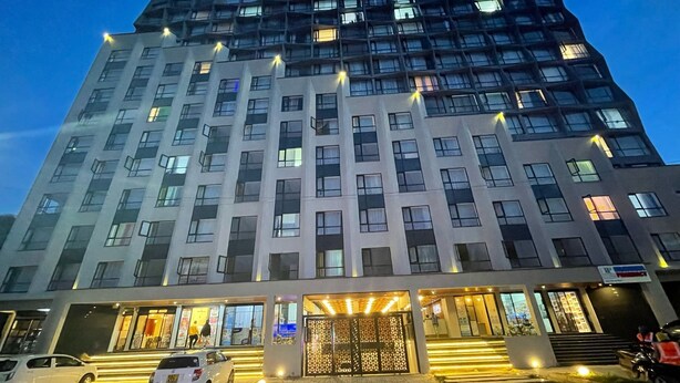 A multi-story hotel with a modern architectural design, featuring a prominent entrance with a decorative gate and illuminated steps. - RnM Haven in Tsavo Apartments 13kms from JKIA
Walk to Stylish,Clean & Comfy Stay (Nairobi)