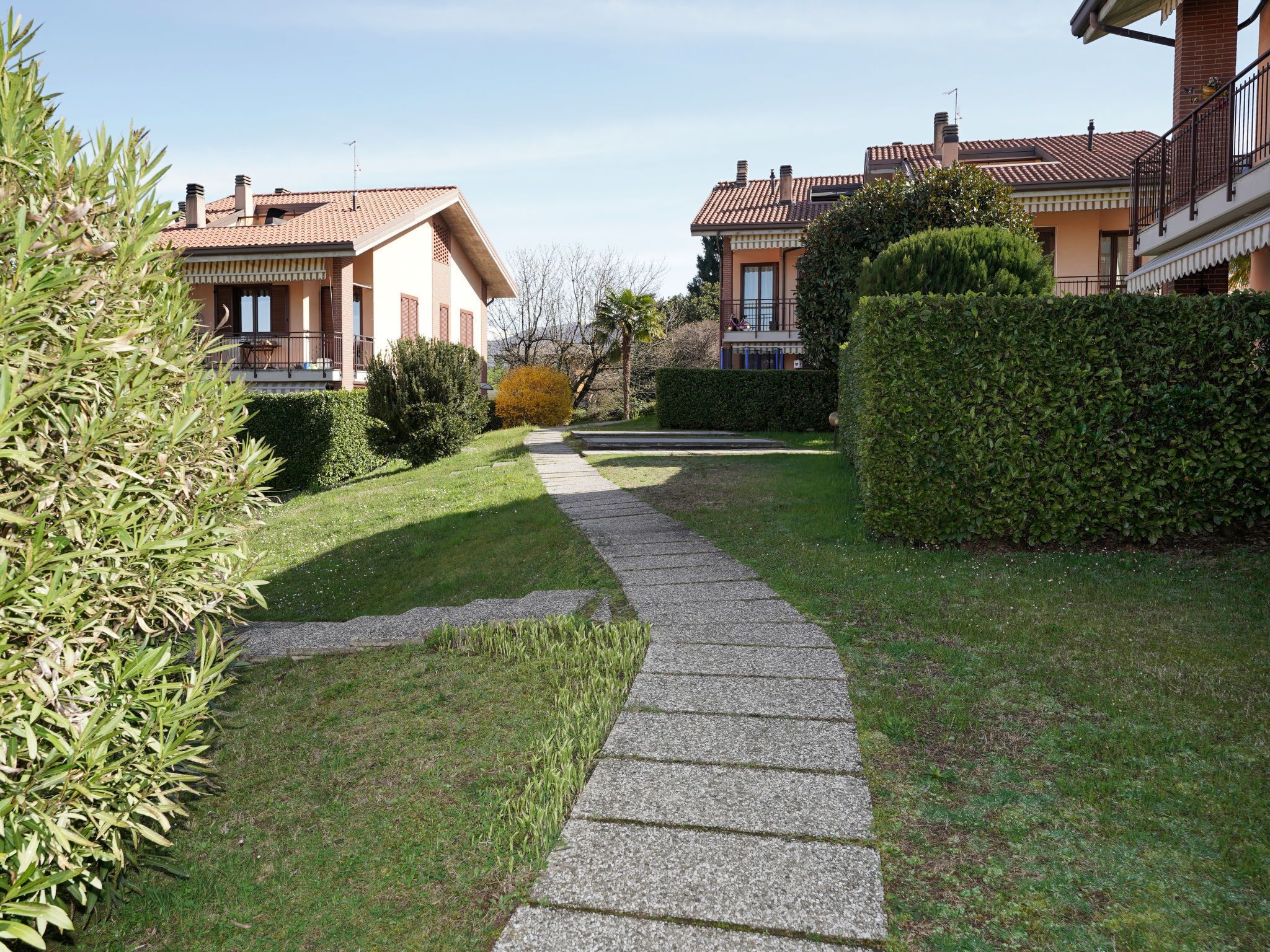 A residential area with a paved pathway leading to houses with tiled roofs.