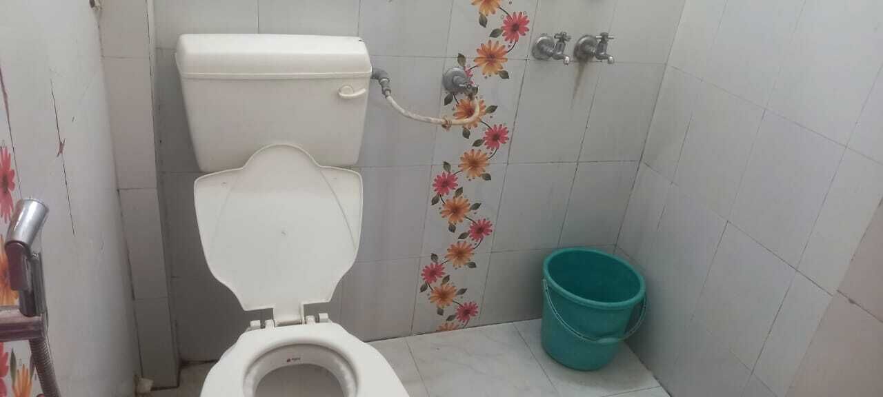 Ein kleines Badezimmer mit Toilette, Dusche und Eimer.