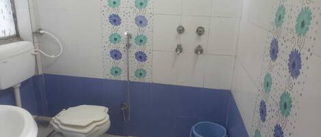 A bathroom with a toilet, shower, and a blue bucket.
