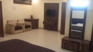 Un dormitorio con una cama, televisión montada en la pared, una mesita y un armario.
