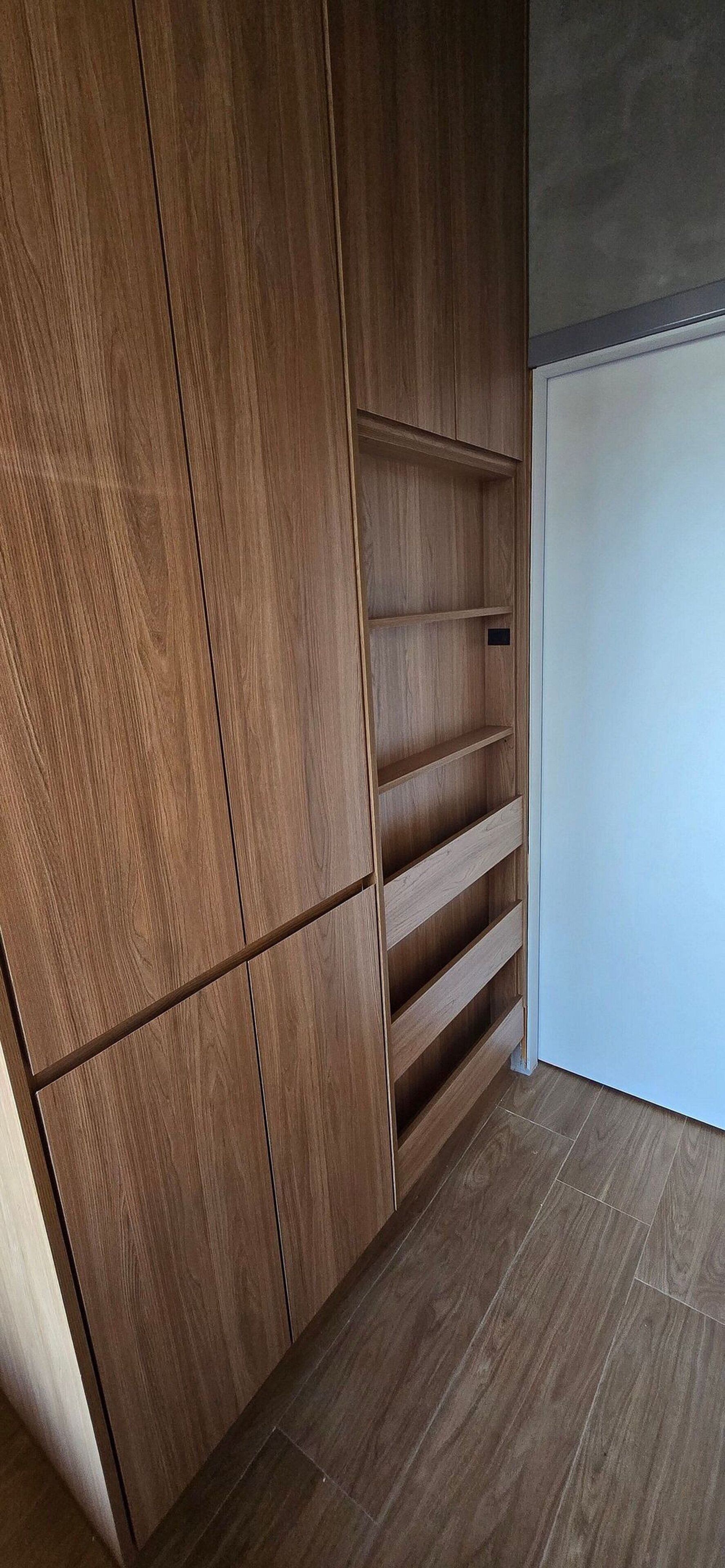 Een houten garderobe met verschillende vakken en een ingebouwde plankkast.