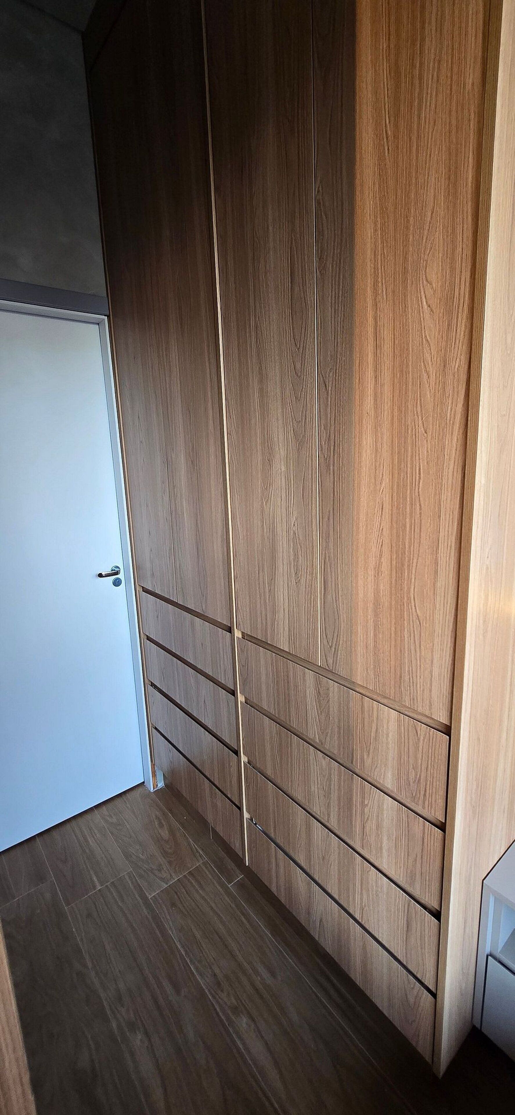 Une pièce avec une armoire en bois, une porte blanche et un sol carrelé.