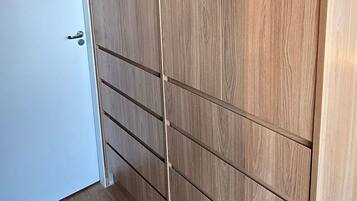 Une pièce avec une armoire en bois, une porte blanche et un sol carrelé.