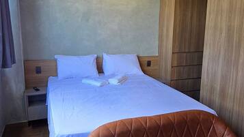 Ein Hotelzimmer mit einem Bett, einem braunen Ledersessel, einem Holzschrank, einem Nachttisch und einer Klimaanlage.