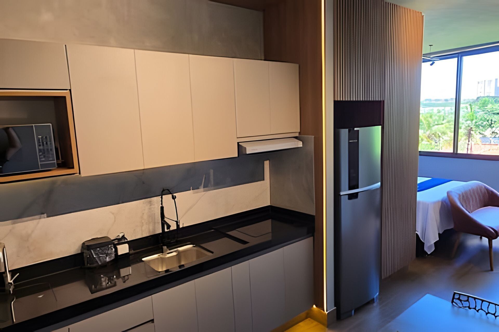 Een moderne keuken met een ingebouwde magnetron, een roestvrijstalen koelkast en een zwart aanrecht.