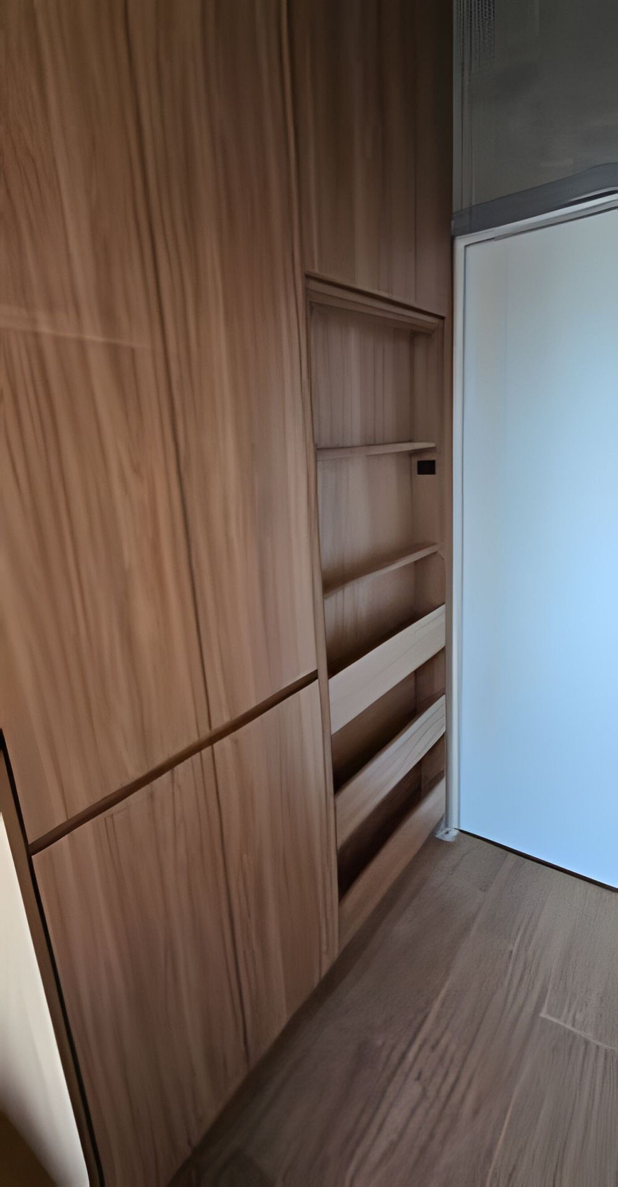 Ein Holzkleiderschrank mit mehreren Einlegeböden und einer weißen Tür.