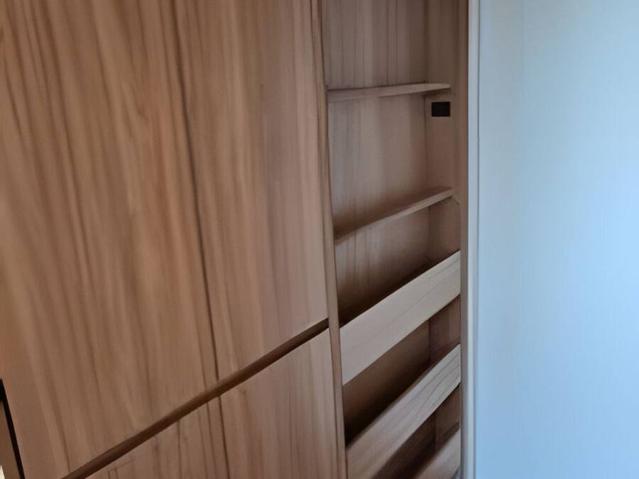 Ein Holzkleiderschrank mit mehreren Einlegeböden und einer weißen Tür.
