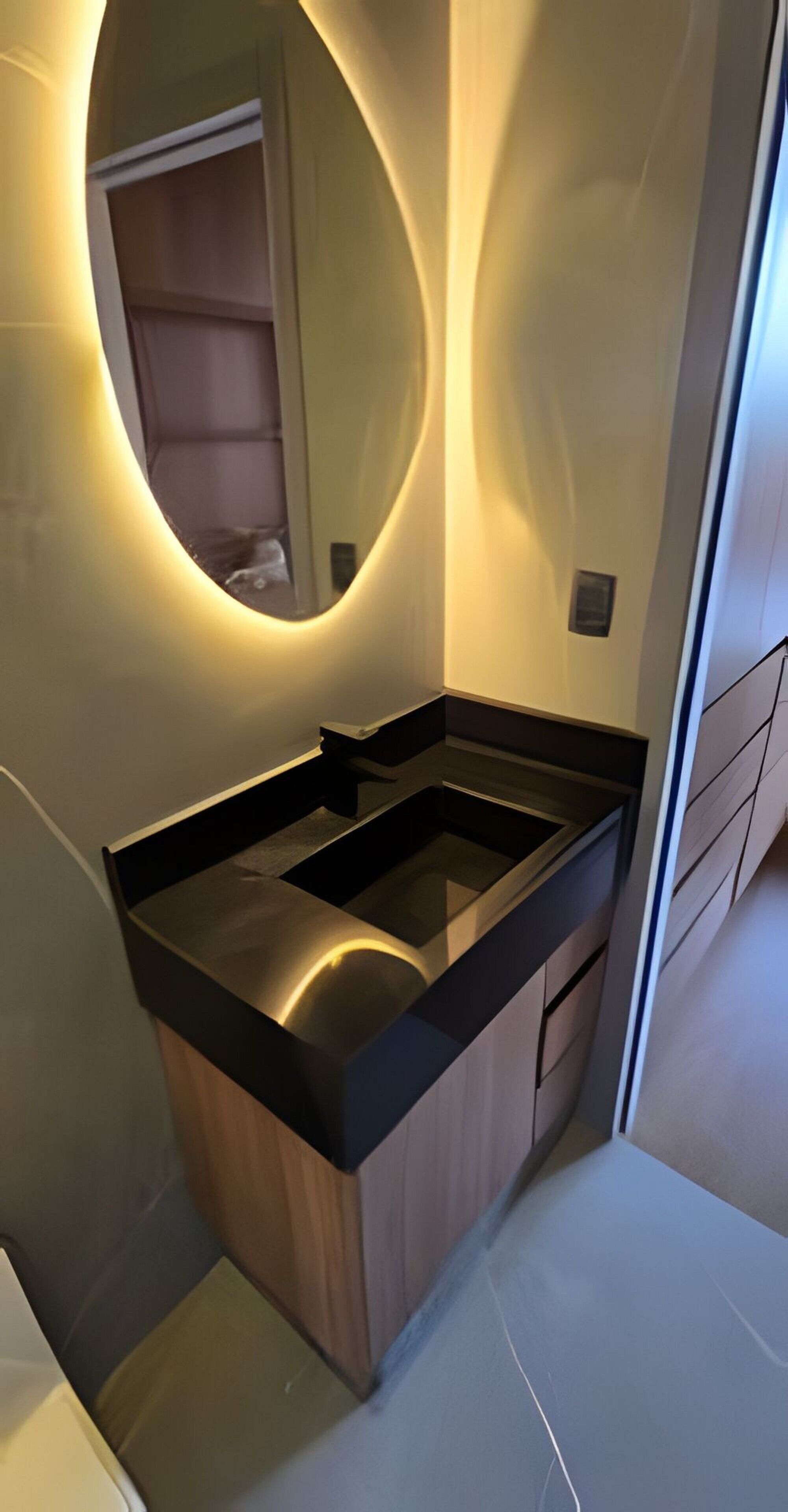Un baño moderno con un mueble de tocador elegante, un espejo grande y un lavabo integrado.