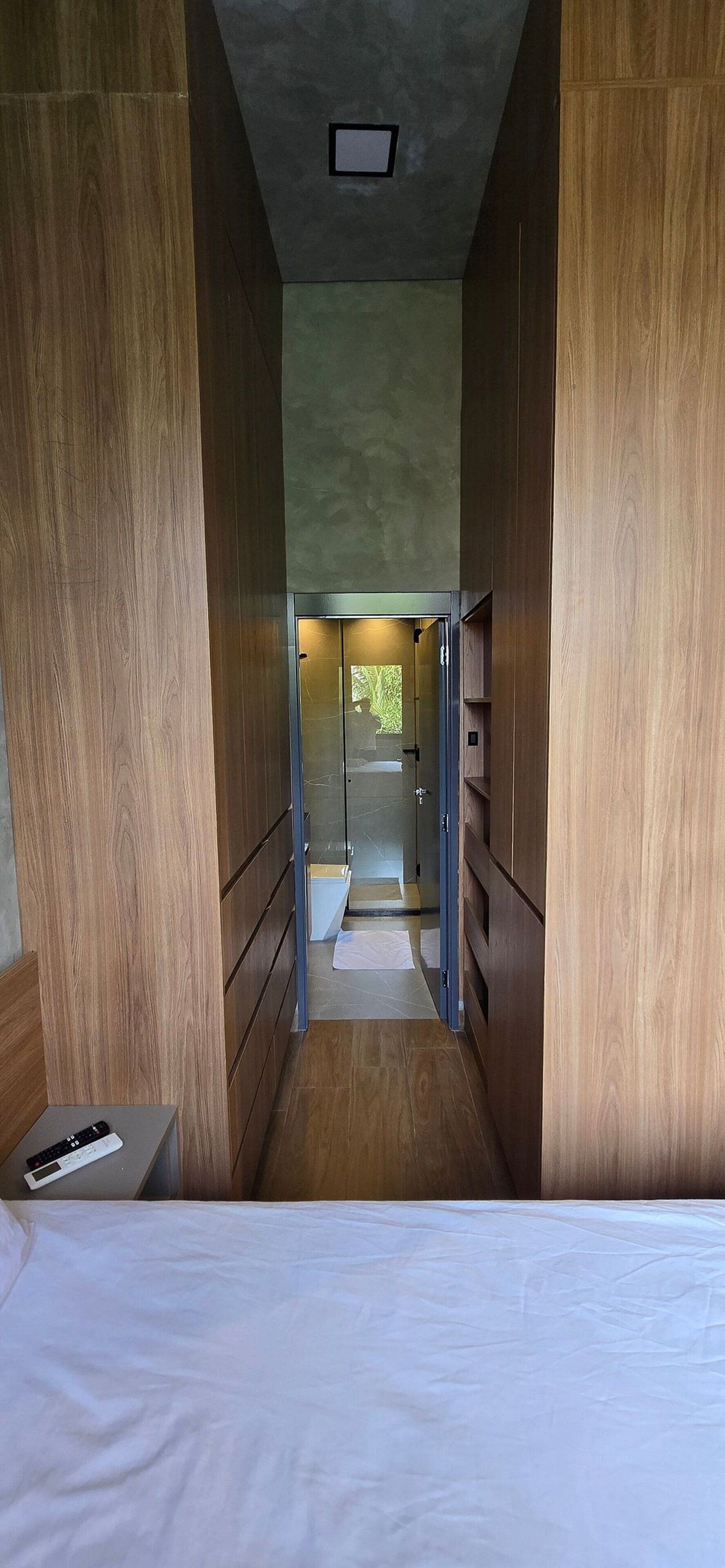 Un pasillo estrecho con paneles de madera que da a un baño.