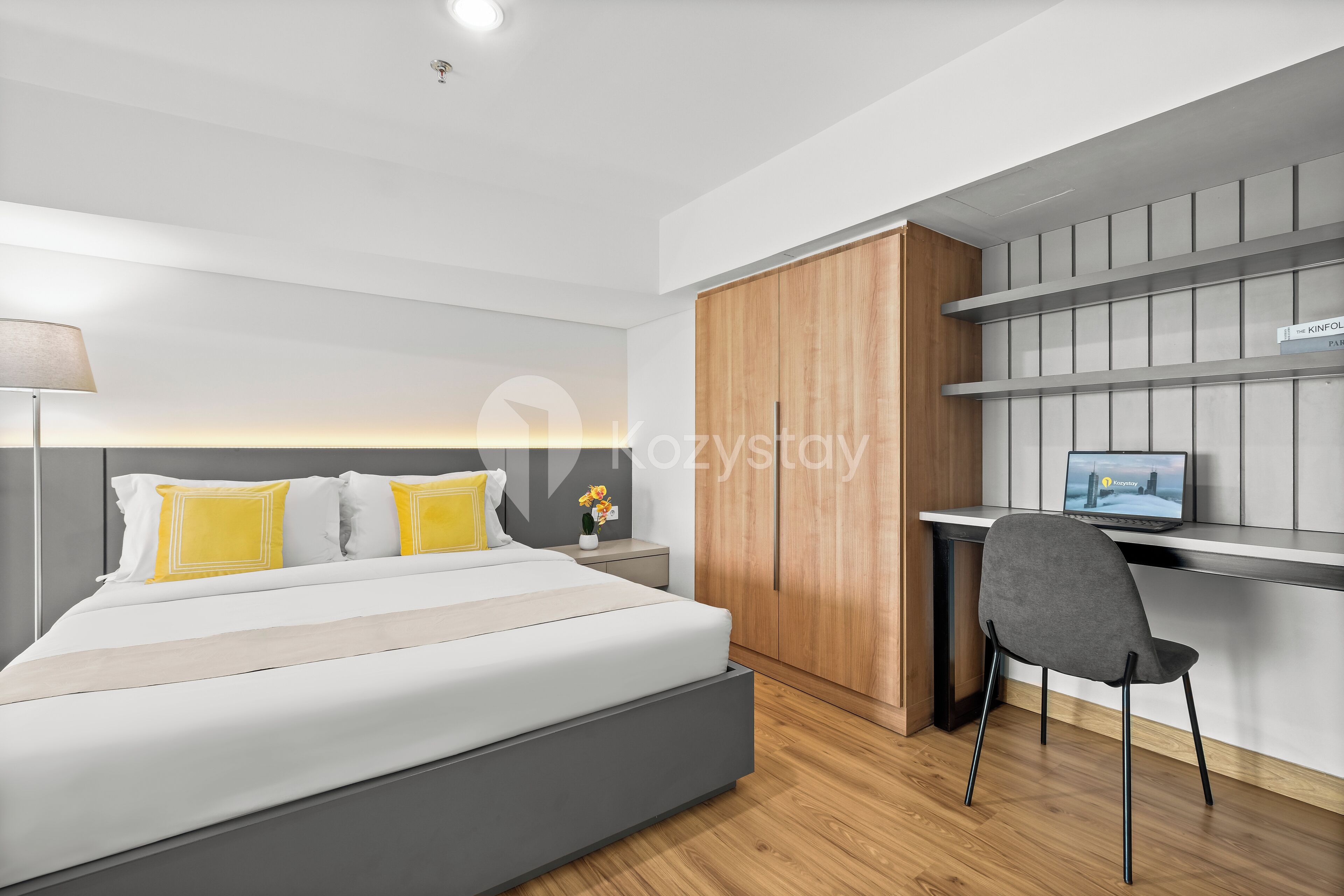 A modern bedroom with a large bed, a desk, and a wardrobe.