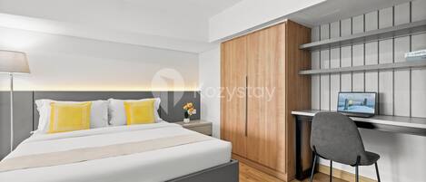 A modern bedroom with a large bed, a desk, and a wardrobe.