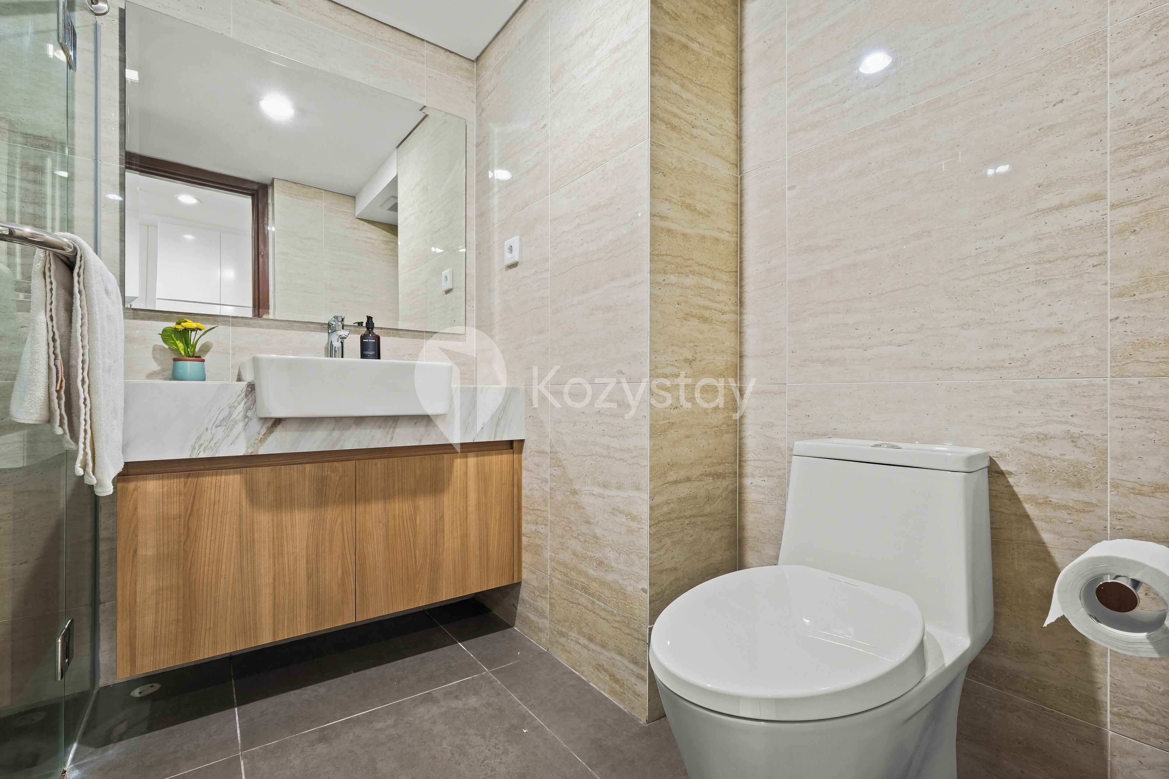 Ein modernes Badezimmer mit Marmorwaschtisch, Toilette und Duschkabine aus Glas.