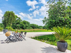 Enjoy al fresco dining in a serene setting with a table for four and a lush green backdrop.