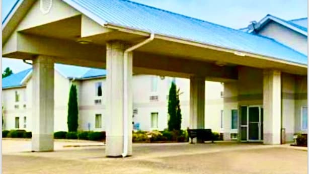 Un hôtel doté d’un espace extérieur abrité, de nombreuses colonnes et d’un bâtiment dont le toit est en pente.