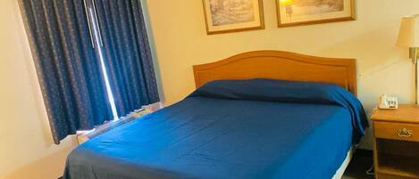 Ein ordentlich bezogenes Bett mit blauer Bettwäsche in einem Hotelzimmer.