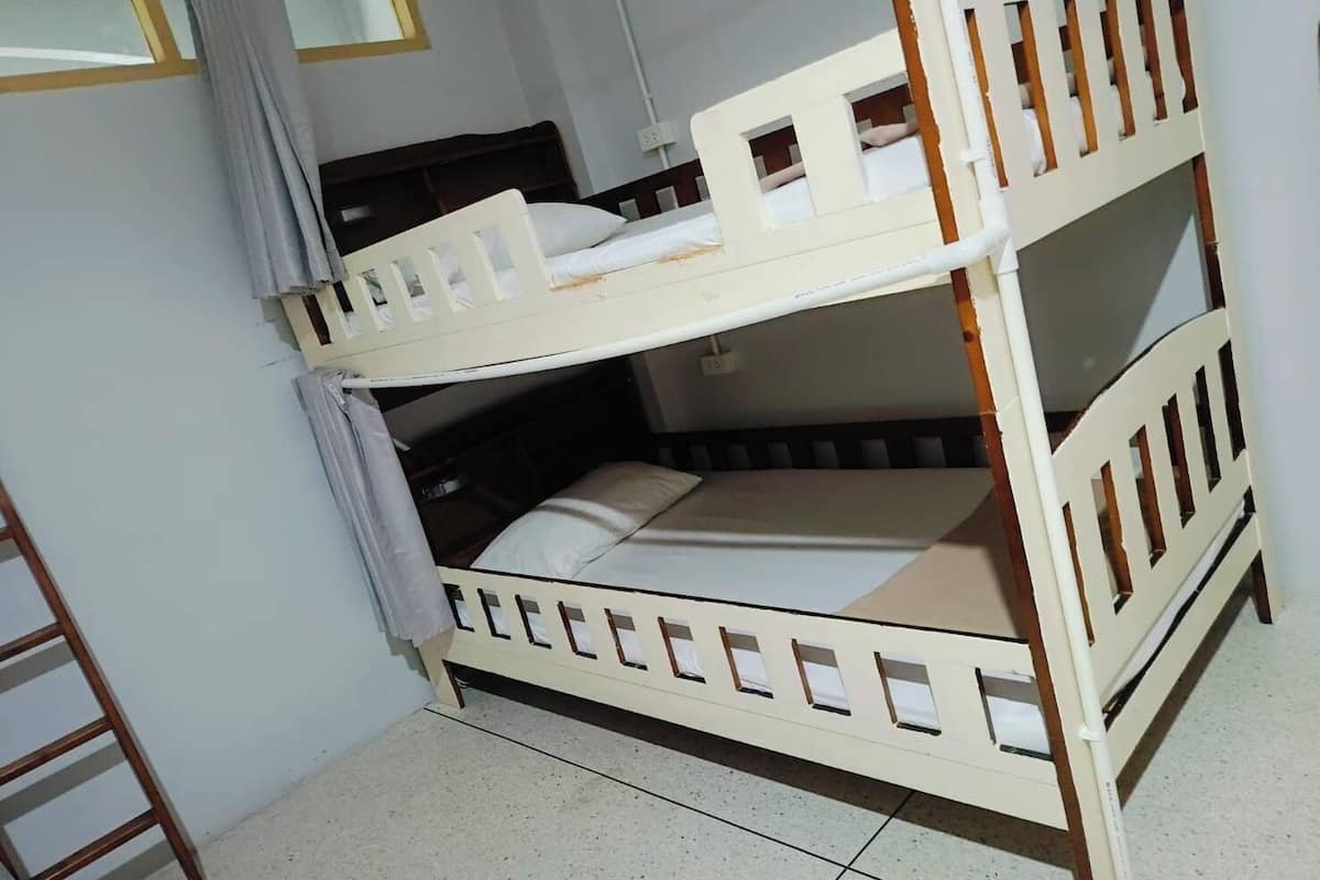 A bunk bed with a ladder, a window, and a wall socket.