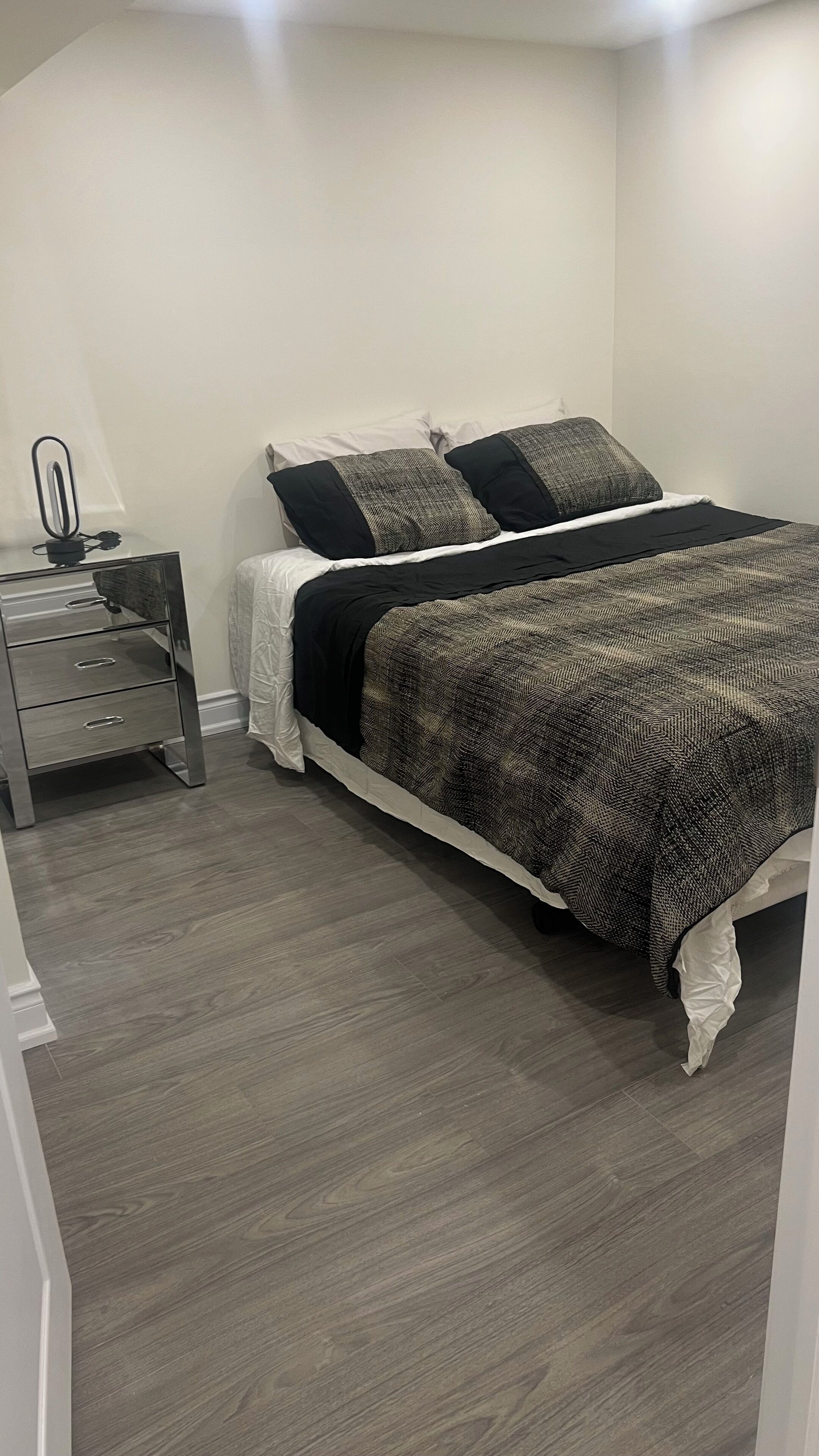 A bedroom with a bed, a nightstand, and a dresser.