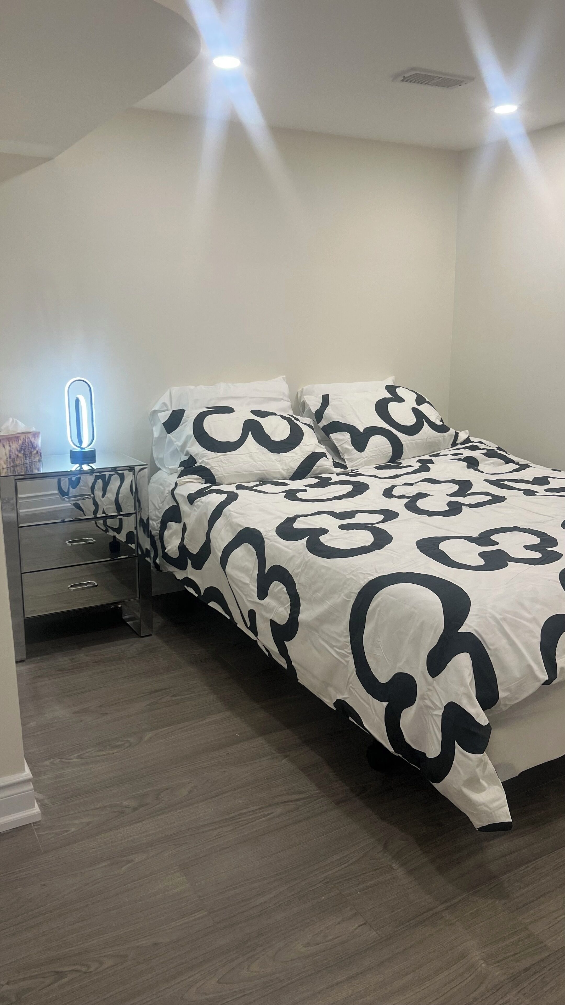 Un dormitorio con cama, mesita de noche y lámpara.