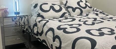 Un dormitorio con cama, mesita de noche y lámpara.