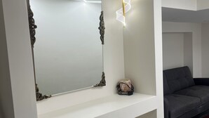 A white console table with a large mirror and a wall-mounted light fixture. - The Luxe Haven (East Gwillimbury)
