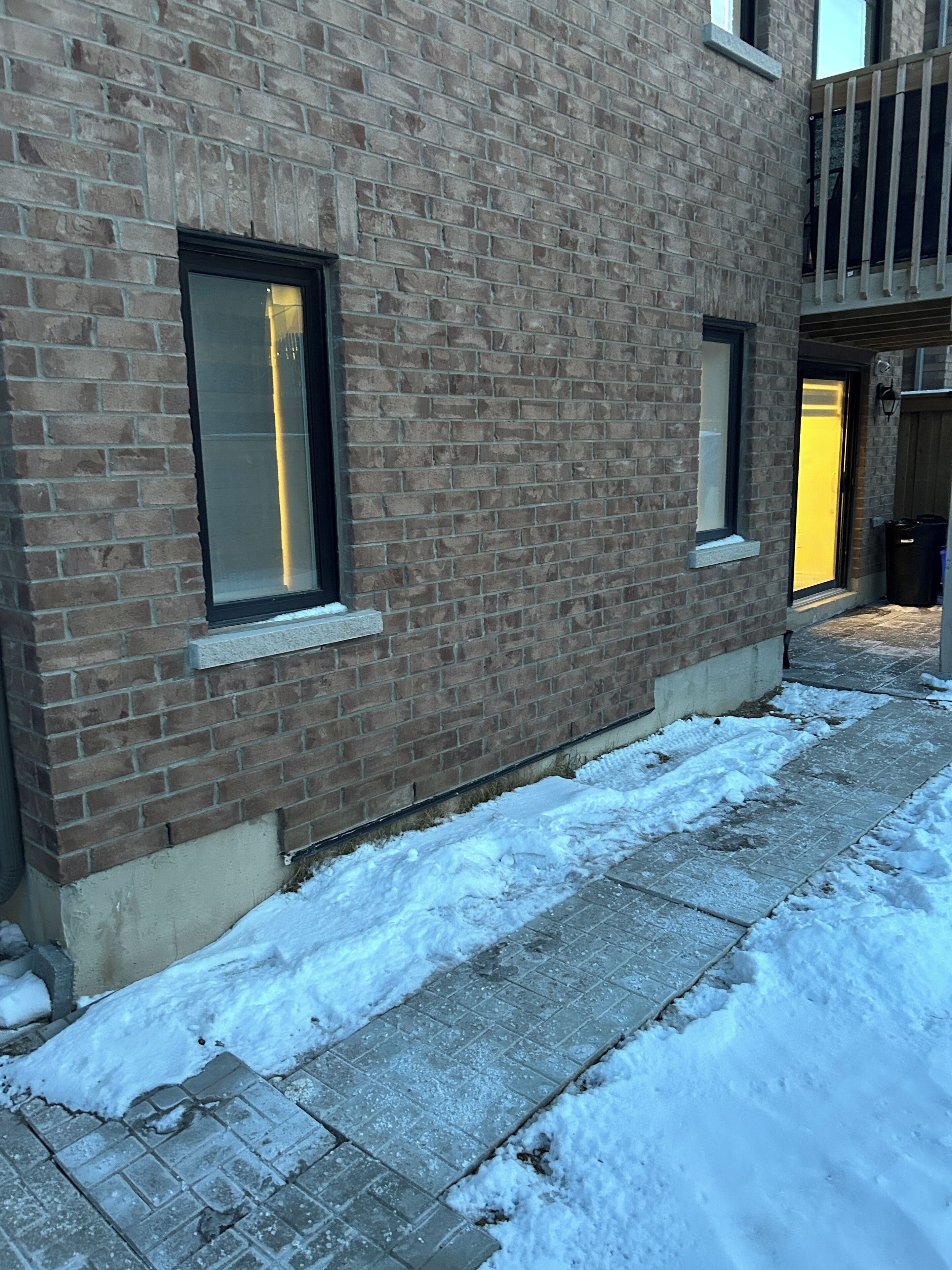 A brick building with two windows and a snow-covered ground.