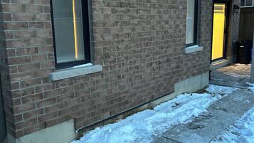 A brick building with two windows and a snow-covered ground.
