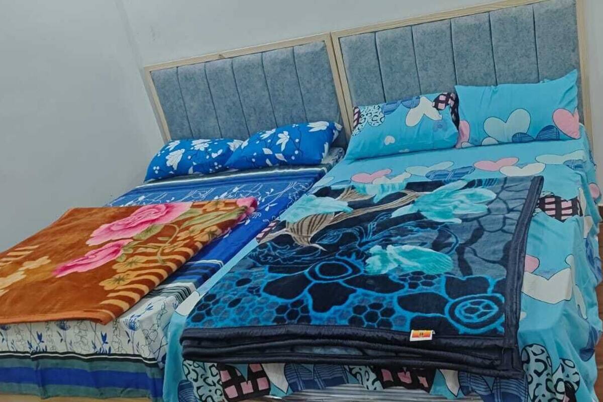 A bed with a grey headboard and blue floral bedding.