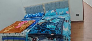 Ein Bett mit grauem Kopfteil und blau blumigem Bettzeug.