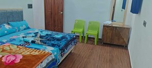 Ein Schlafzimmer mit einem Bett, zwei grünen Stühlen, einem Holzschrank und einem Spiegel.