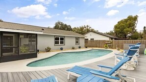 A backyard with a swimming pool, deck chairs, and a house. - Pool Party in Daytona! Sleeps 8 (Holly Hill)