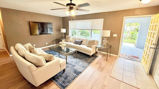 A spacious living room with a sofa, coffee table, and a ceiling fan. - Pool Party in Daytona! Sleeps 8 (Holly Hill)