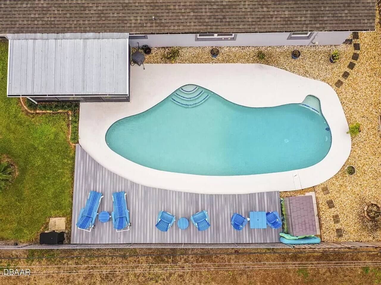 An aerial view of a backyard with a swimming pool, deck, and lounge chairs.
