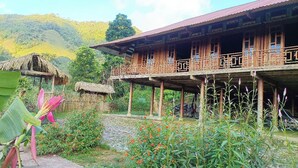 A traditional wooden house with a balcony, surrounded by lush greenery and a stone pathway. - Ban Lien Forest Homestay Lao Cai (Ban Lien)