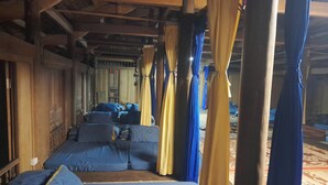 A room with wooden beams, a bed with blue bedding, and curtains in yellow and blue. - Ban Lien Forest Homestay Lao Cai (Ban Lien)