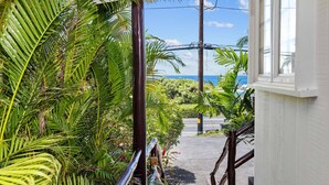 A staircase leading to a balcony with lush tropical plants and a view of the ocean. - Butterfly House:  Beautiful Ali'i Drive Home with Ocean Views! (Kailua-Kona)