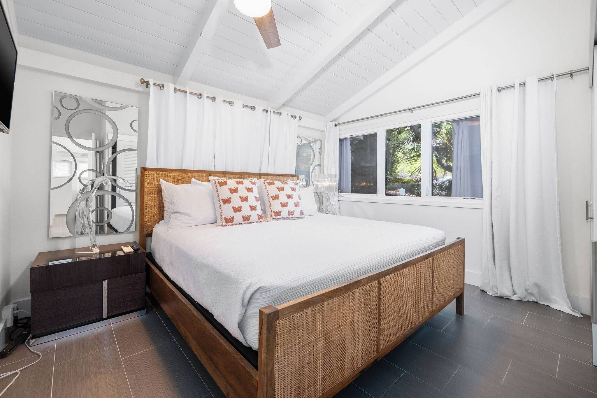 A modern bedroom with a wooden bed, white bedding, and a nightstand.