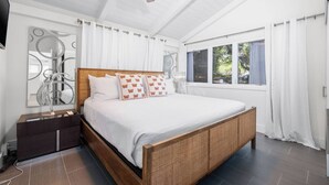 A modern bedroom with a wooden bed, white bedding, and a nightstand. - Butterfly House:  Beautiful Ali'i Drive Home with Ocean Views! (Kailua-Kona)