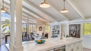 A spacious kitchen with a large island, pendant lighting, and a view of the outdoors. - Butterfly House:  Beautiful Ali'i Drive Home with Ocean Views! (Kailua-Kona)